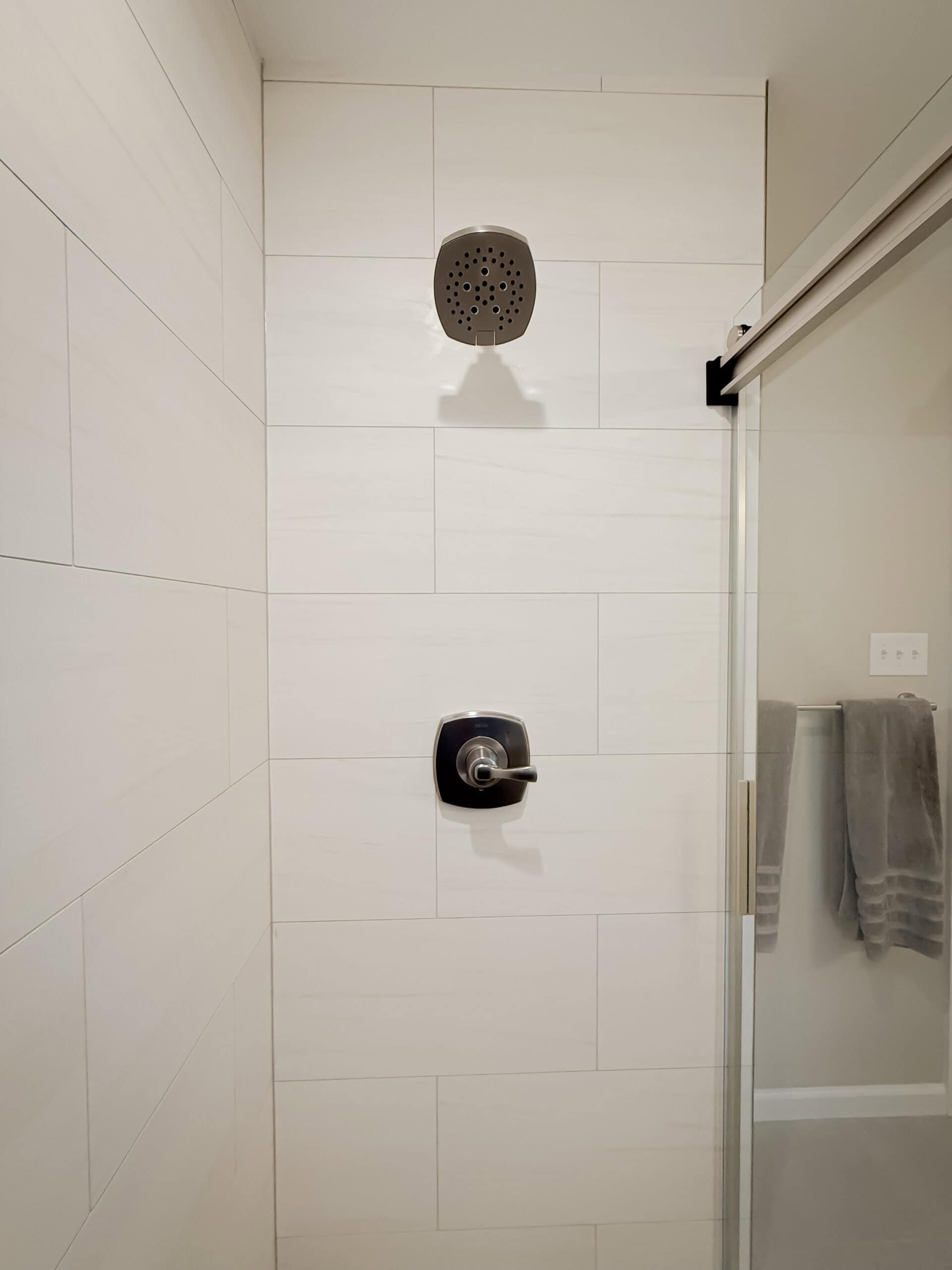 A shower with a shower head and a towel rack.