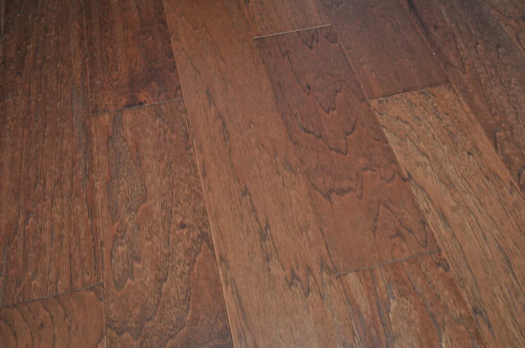 Close-up of polished, reddish-brown hardwood floor planks with visible wood grain patterns and slight color variations. The planks are laid side by side, creating a smooth, natural-looking surface.