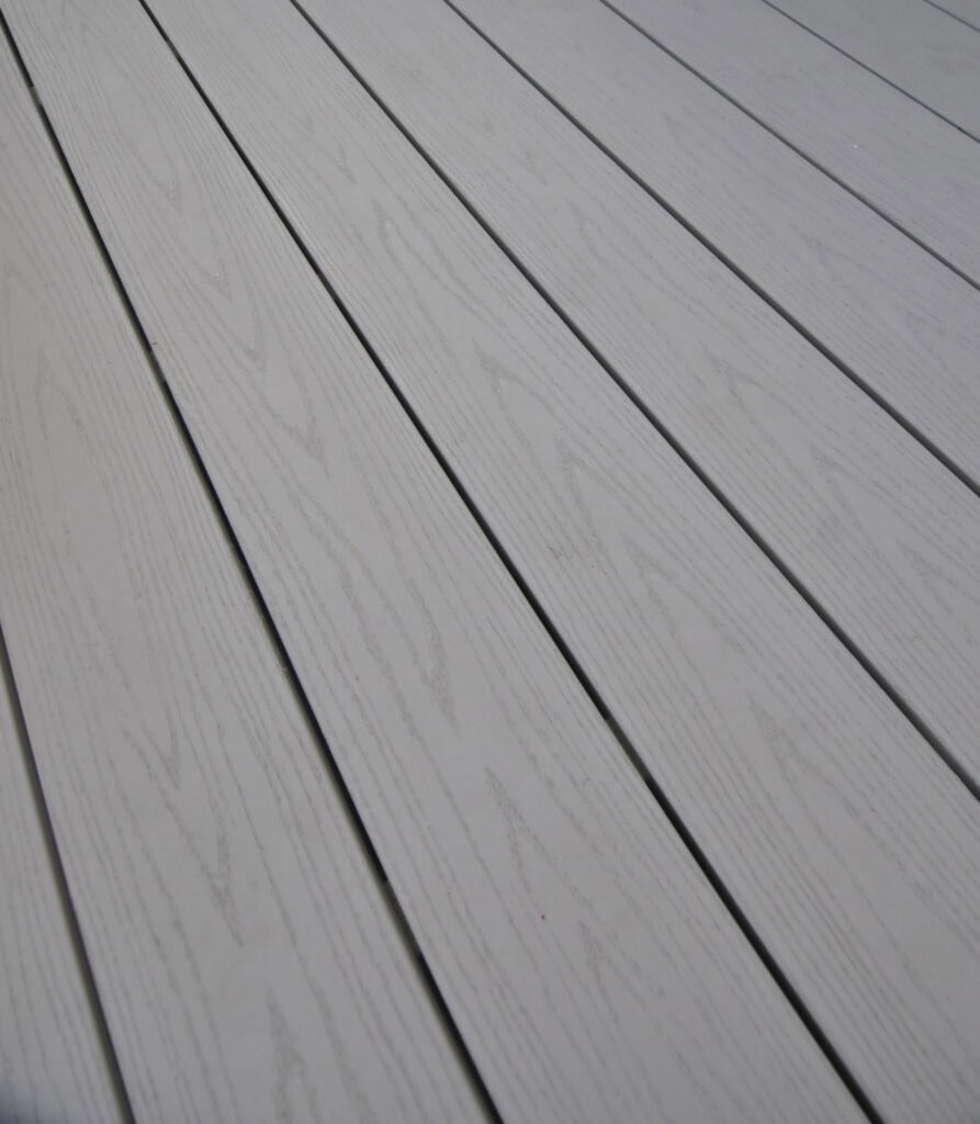Close-up of clean, light gray wooden planks laid side by side, showing subtle wood grain patterns and faint grooves between each board. The surface appears smooth and well-maintained.