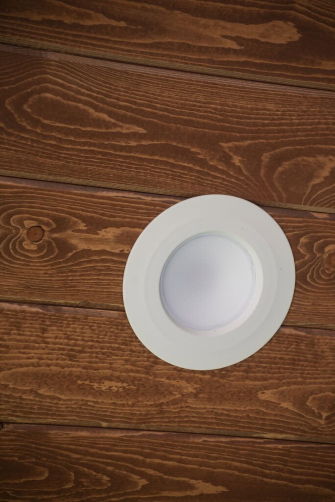 A white round plate placed on a wooden surface with a distinct grain pattern, viewed from above.