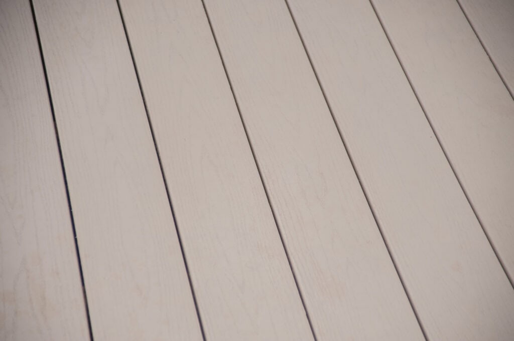 Close-up of light beige wooden planks laid side by side, showing subtle wood grain patterns and thin gaps between each plank.