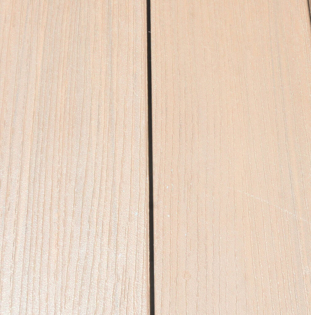 Close-up of two light brown wooden planks with a narrow dark gap between them, showing wood grain texture and subtle surface details.