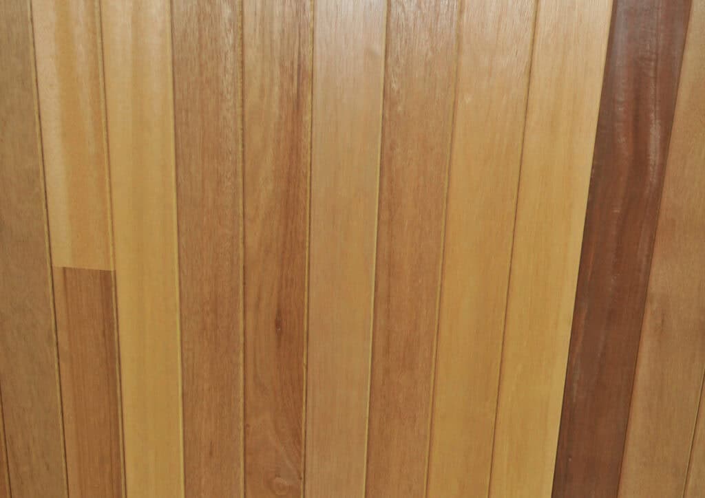Wooden planks arranged vertically with varying shades of light and dark brown, showing natural grain patterns and smooth surfaces.