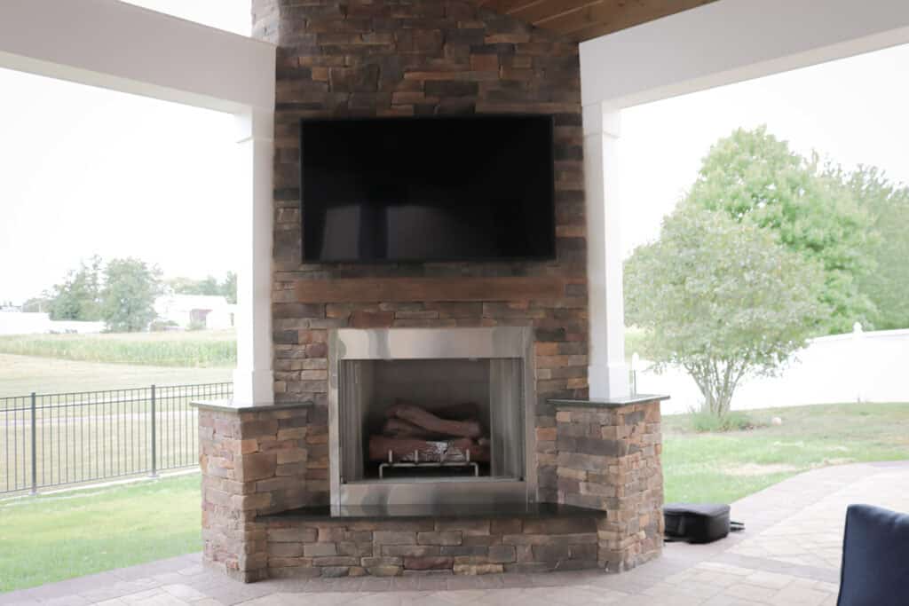 A tv mounted on a brick fireplace.