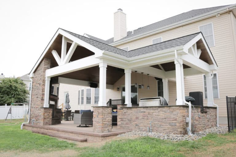 A covered patio with a grill and a covered porch.
