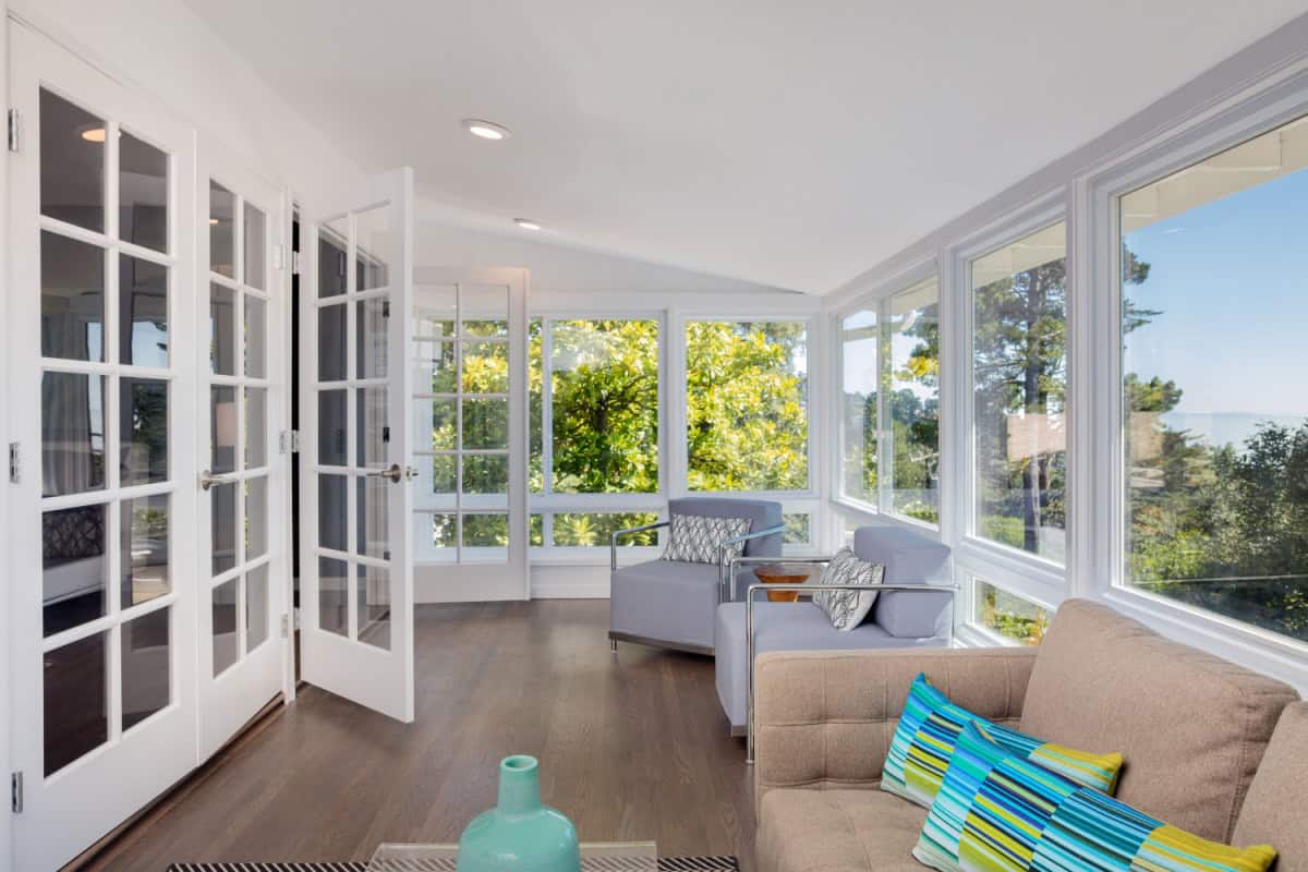 Sunroom with picture windows, two armchairs, and a love seat