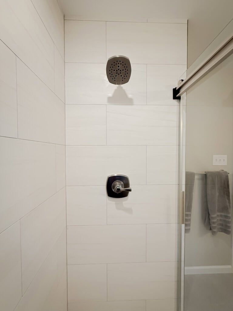 A shower with a shower head and a towel rack.