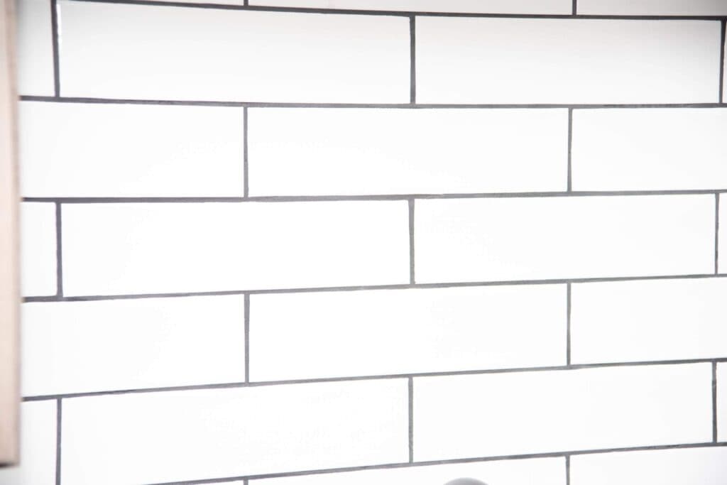 White rectangular subway tiles with dark grout create a clean, modern, and minimalist wall pattern. The tiles are aligned in a horizontal, staggered brick-like arrangement.