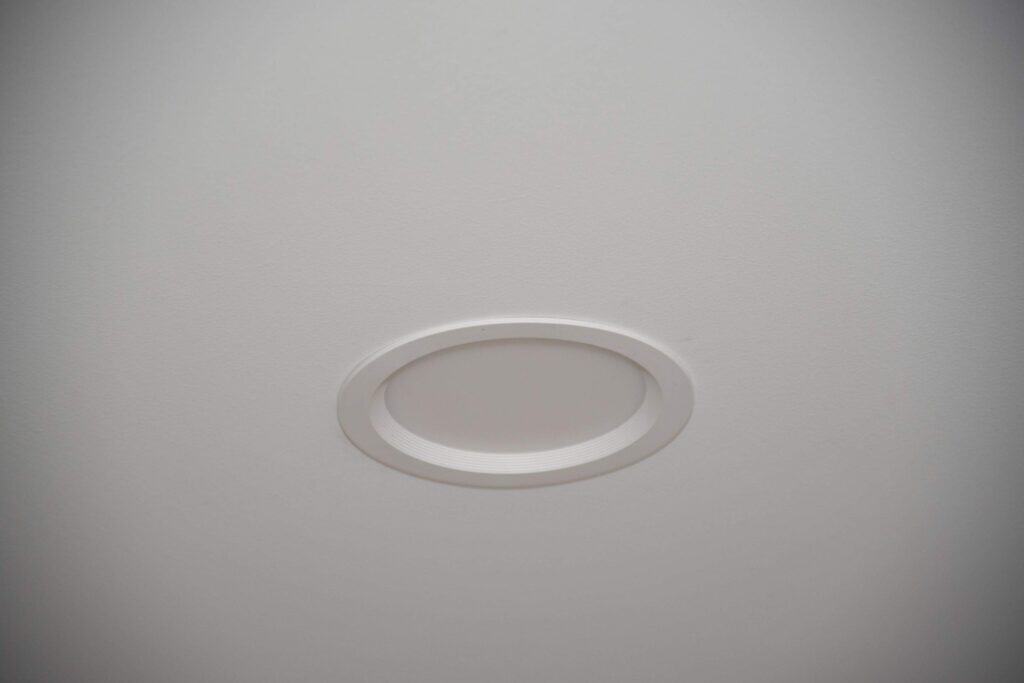 A close-up view of a recessed ceiling light fixture on a smooth, white ceiling.