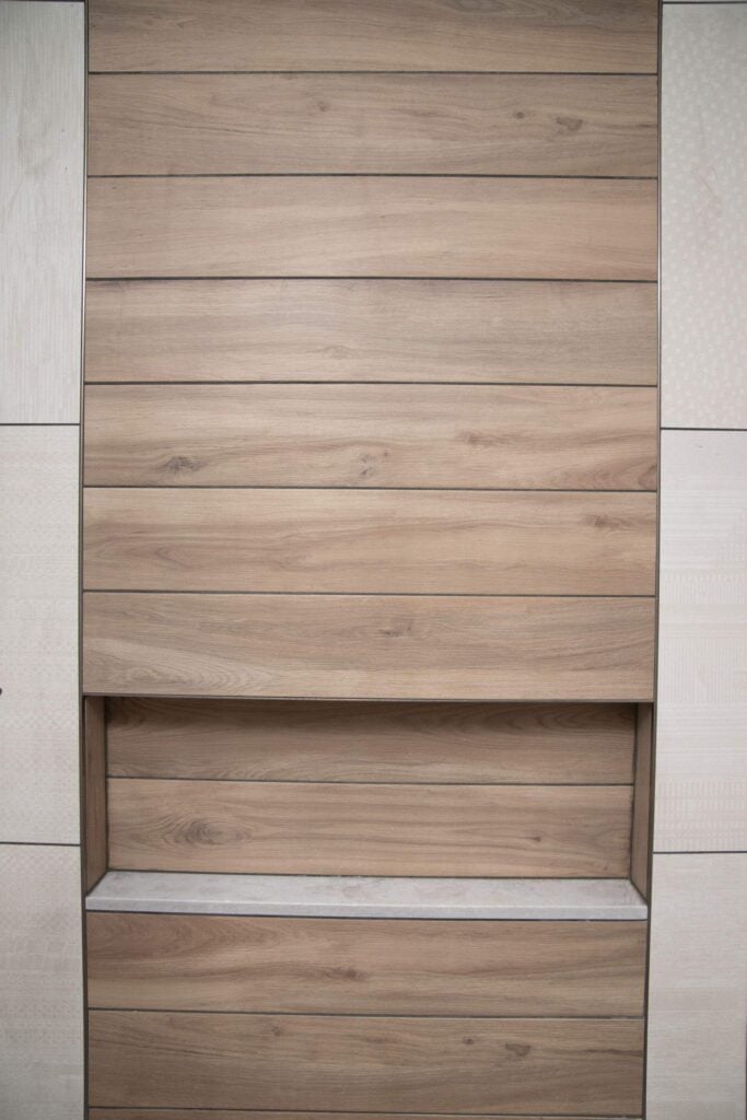 A wall with horizontal wooden panels featuring a recessed shelf in the center, also lined with wood, against a light-colored background.