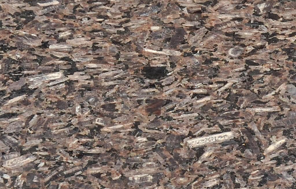Close-up of a textured granite surface with a mix of brown, black, and beige mineral flecks, creating a speckled and layered appearance.