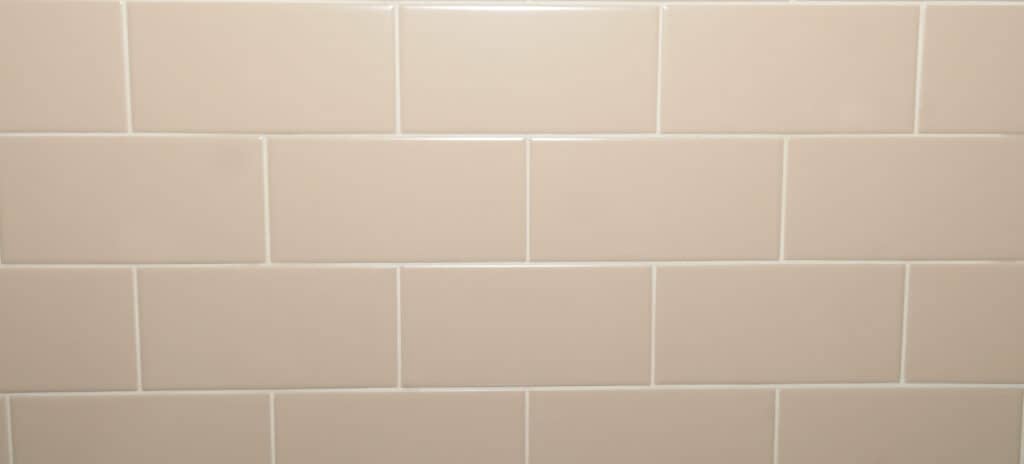 Beige rectangular ceramic tiles arranged in a horizontal subway pattern with white grout lines.