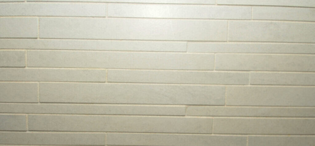 Light grey rectangular tiles arranged in a staggered horizontal pattern, forming a smooth, modern wall surface. The grout lines are thin and evenly spaced.