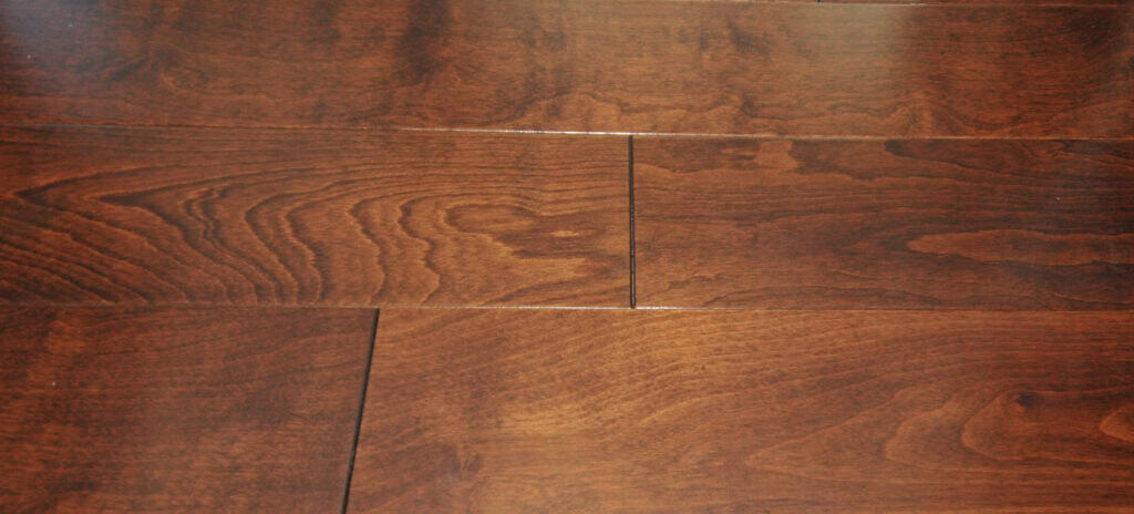 Close-up of polished wooden floorboards with a rich brown color and visible natural grain patterns. The planks are aligned horizontally, showing slight gaps between some of them.
