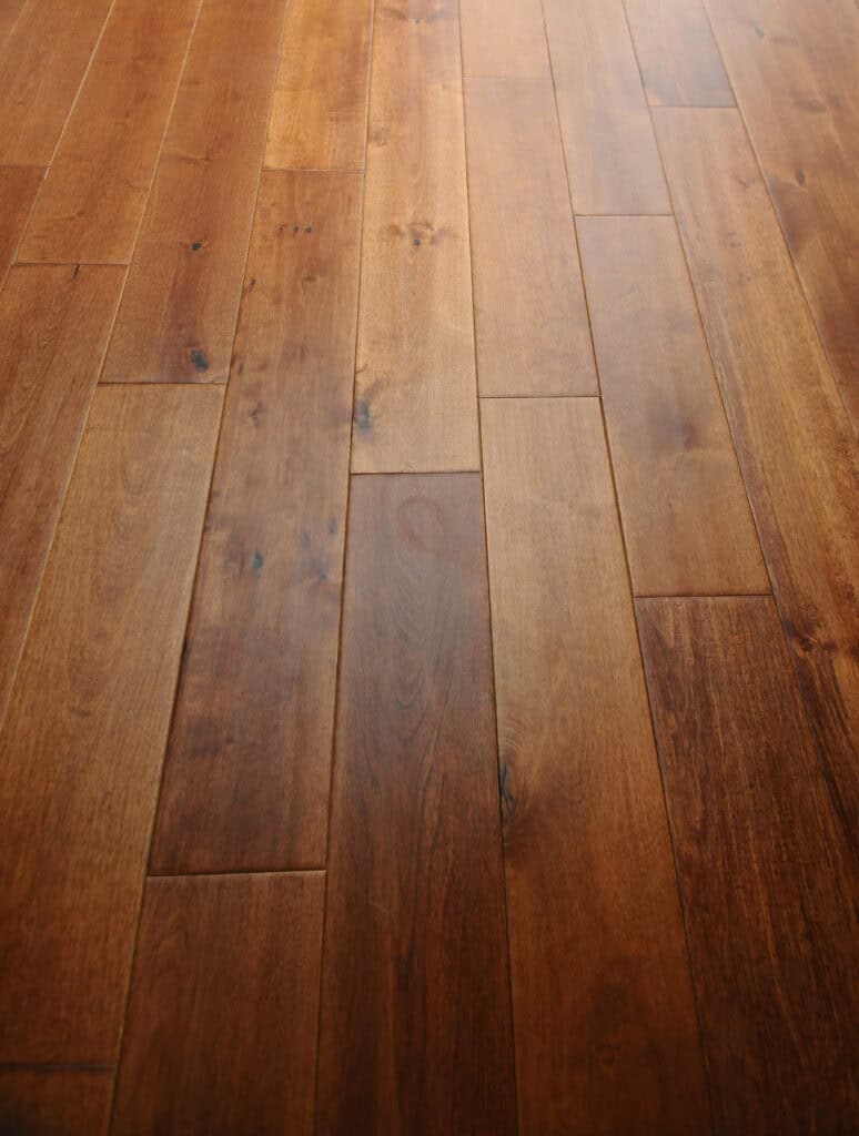 Close-up view of wooden floorboards with a smooth, glossy finish and natural variations in wood grain and color.