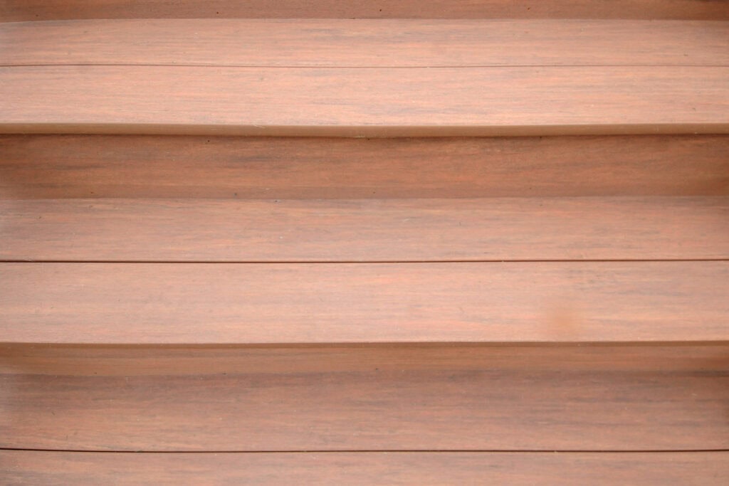 Close-up view of several wooden steps, evenly spaced and parallel, showing the smooth texture and natural brown color of the wood. No visible decorations or objects on the steps.
