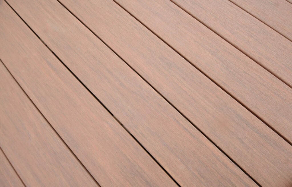 A close-up view of evenly spaced, light brown wooden planks arranged diagonally, showing the smooth texture and slight grain variations on the surface.