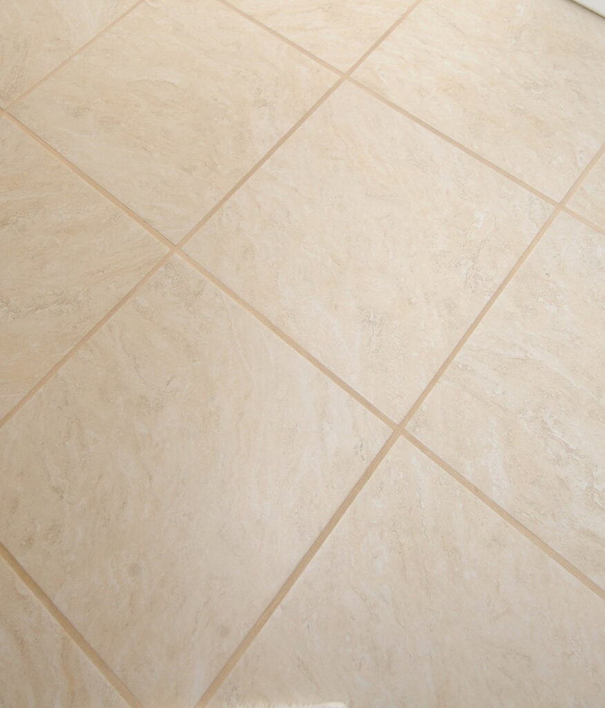 Beige ceramic floor tiles arranged in a grid pattern with light-colored grout lines, creating a clean and smooth surface.