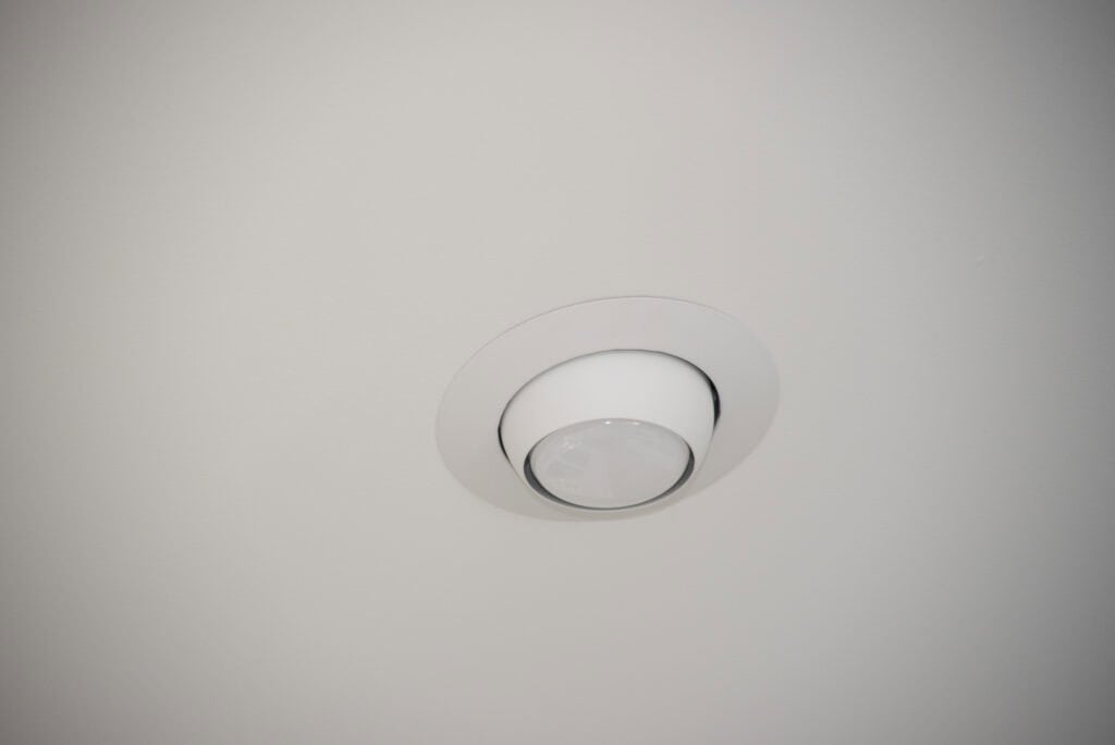 A white recessed ceiling light fixture with a circular trim, installed in a smooth, light-colored ceiling.