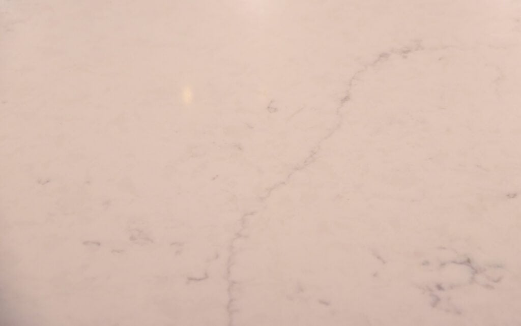 A close-up of a light-colored marble surface with subtle gray veining and a smooth, polished finish.