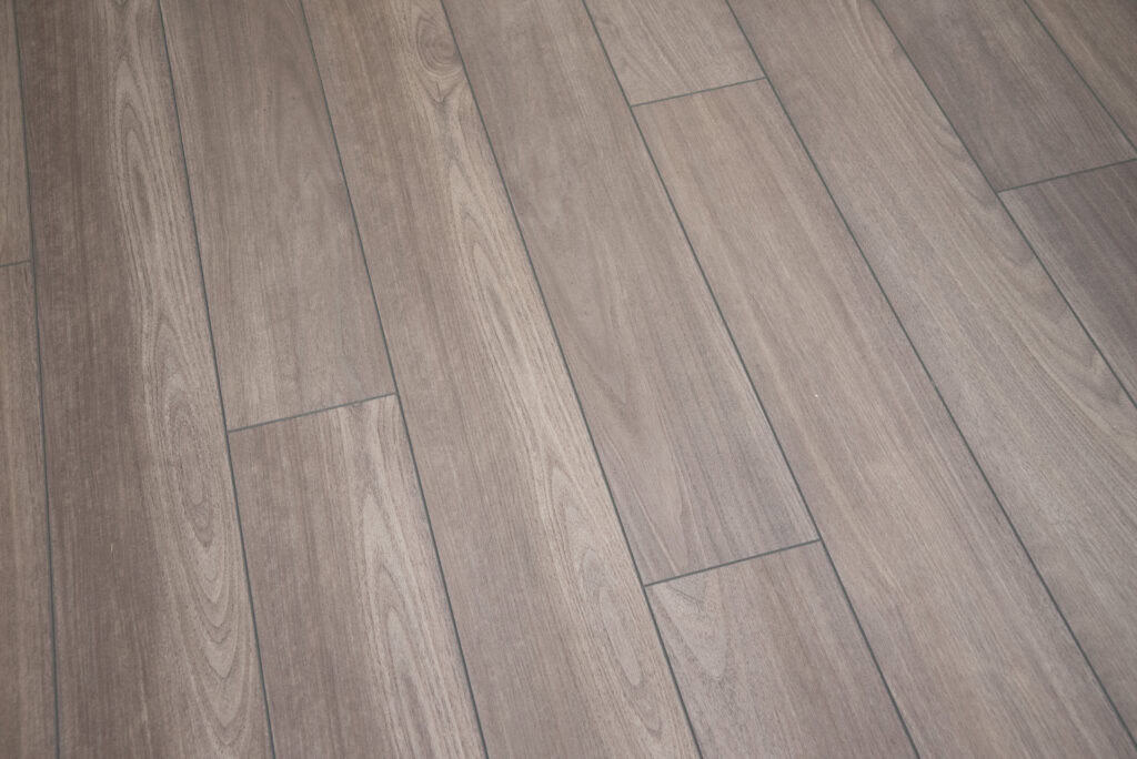 A close-up view of wooden floor planks arranged in a staggered pattern, showcasing a natural brown finish and visible wood grain texture.