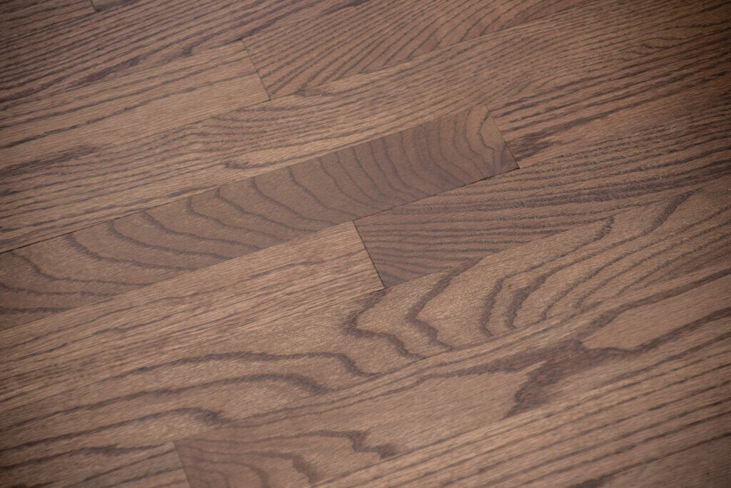 Close-up view of wooden floorboards with a natural brown finish, showing distinct wood grain patterns and subtle color variations across the planks.