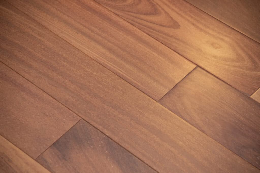Close-up view of smooth, reddish-brown wooden floor planks with natural grain patterns and a warm finish.