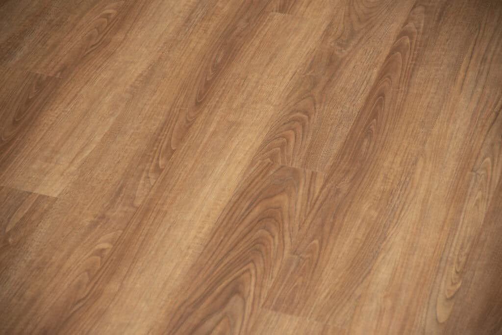 Close-up view of a wooden floor with a smooth surface and natural-looking grain patterns in warm brown tones.