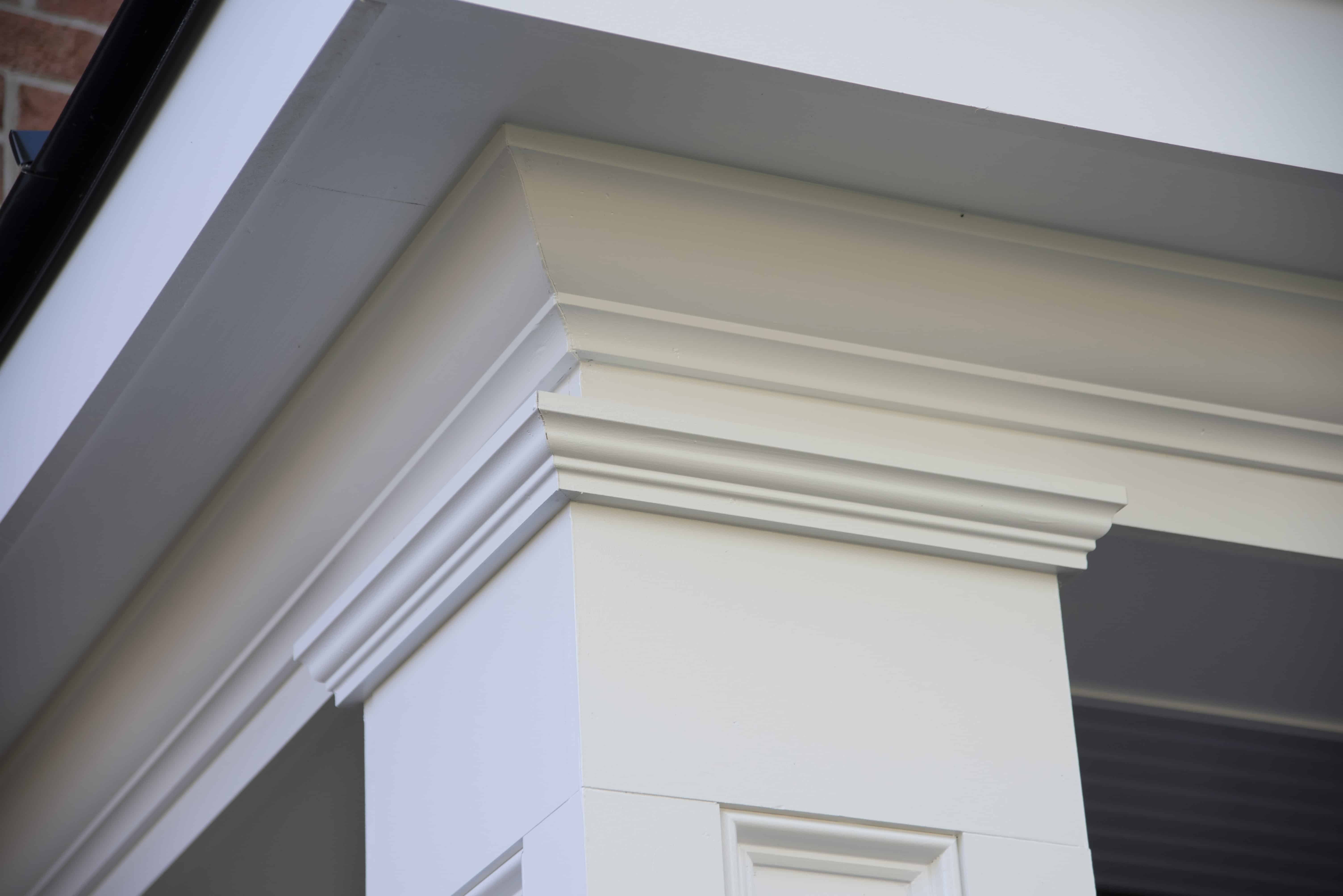 Close-up view of a white, decorative column with detailed molding and trim, part of a buildings exterior. The image highlights the clean lines and architectural features near the roofline.