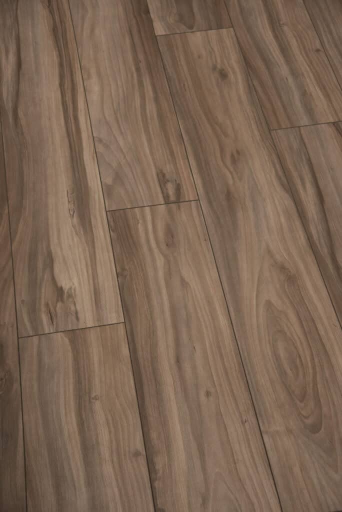 Close-up view of wooden floorboards with a natural brown grain pattern and subtle knots, showing the texture and alignment of the planks.