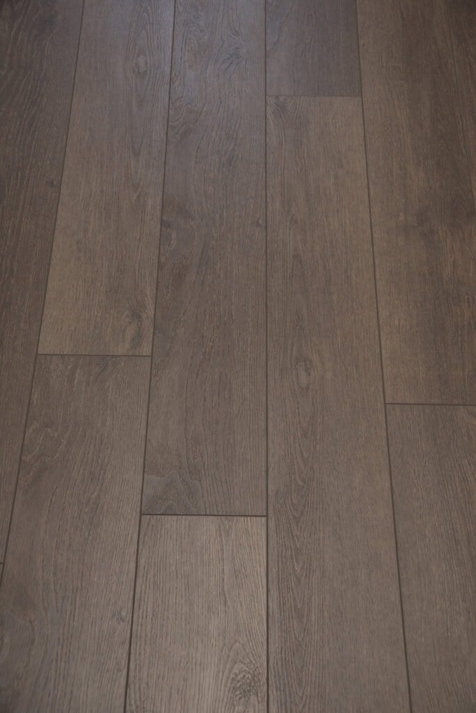 Close-up view of brown wooden floorboards arranged in a staggered pattern, showing natural wood grain texture and subtle color variations.