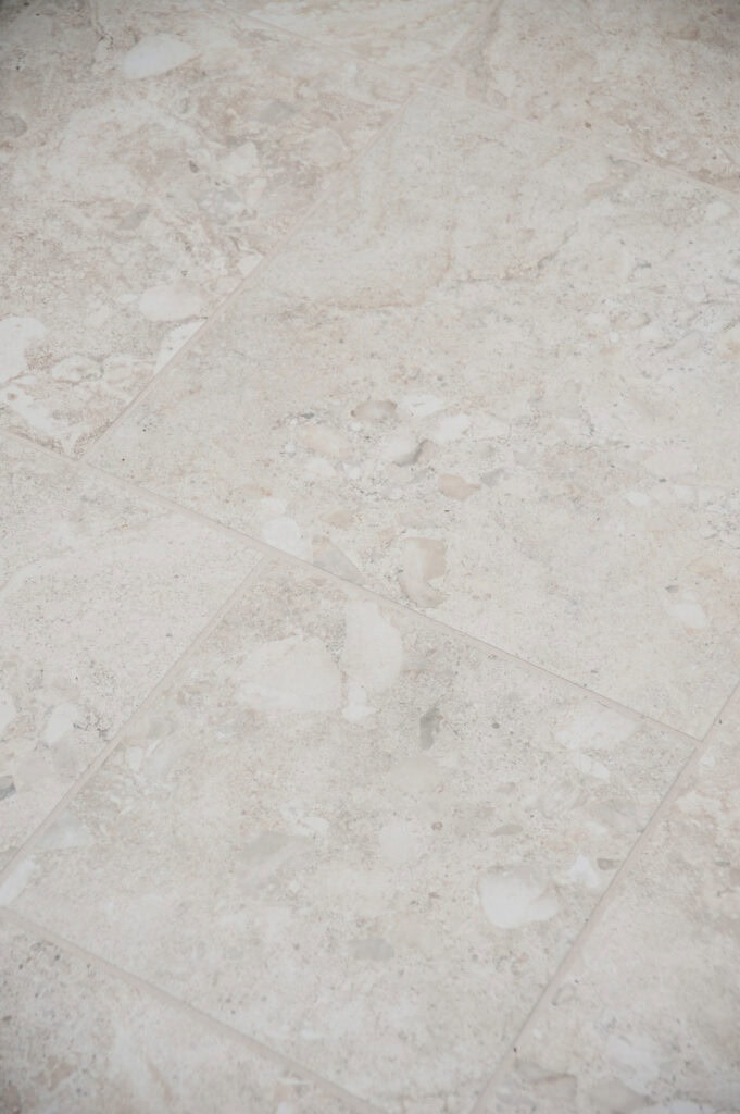 Close-up view of beige and light brown marble tiles with natural patterns and subtle veining, creating a smooth and elegant flooring surface.