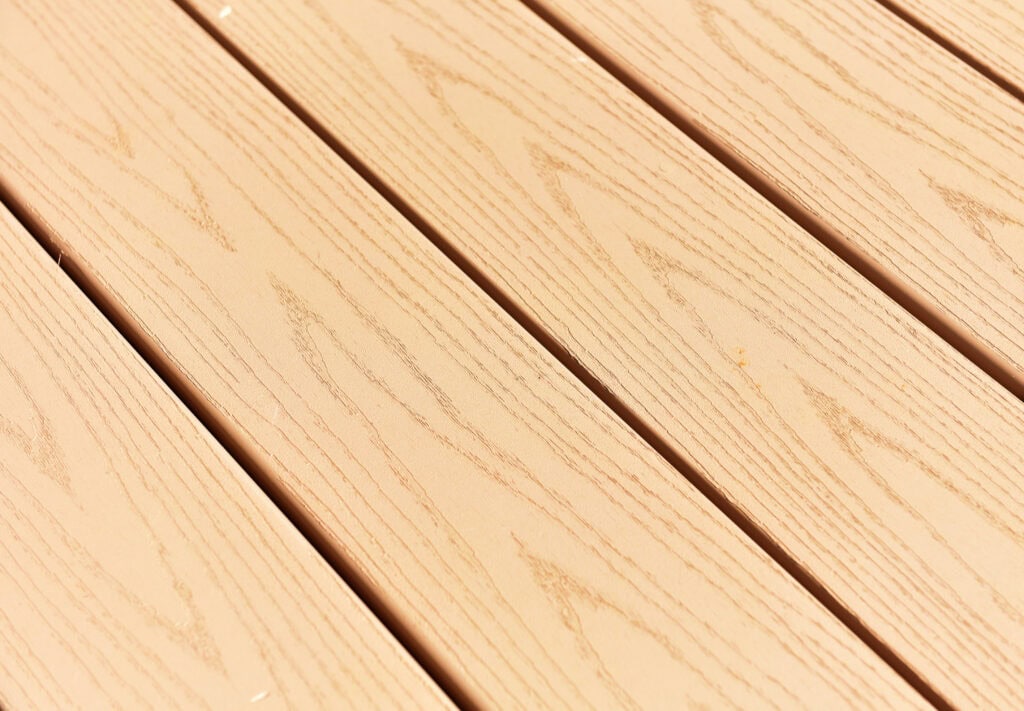 Close-up of light-colored wooden planks arranged parallel to each other, showing natural wood grain patterns and subtle variations in color and texture.