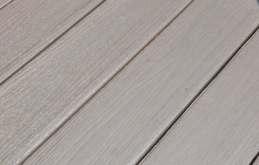 Close-up view of light gray wooden planks arranged side by side, showing their textured grain and subtle grooves between each board. The surface appears clean and well-maintained.