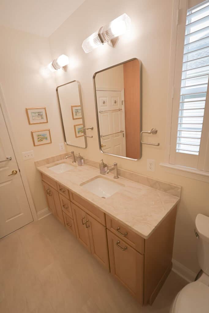 Bathroom vanity with dual sinks, large mirrors, and modern lighting fixtures.