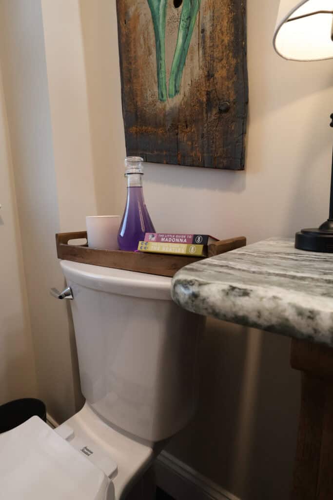 Bathroom with decorative wall art, marble countertop, and toilet with accessories.