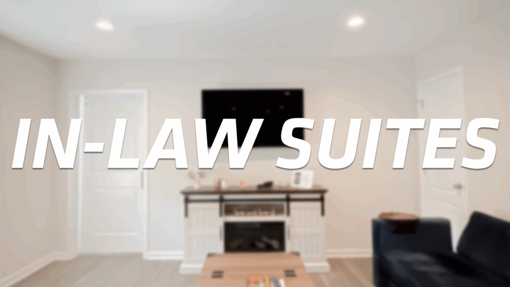A modern, cozy living room with a TV mounted above a fireplace, a white door on the left, and a navy couch on the right. Bold white text across the image reads IN-LAW SUITES.