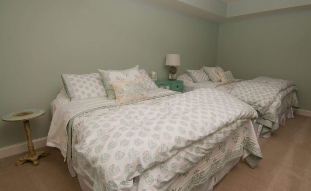 Basement bedroom with two beds, soft pastel walls, and cozy decor.