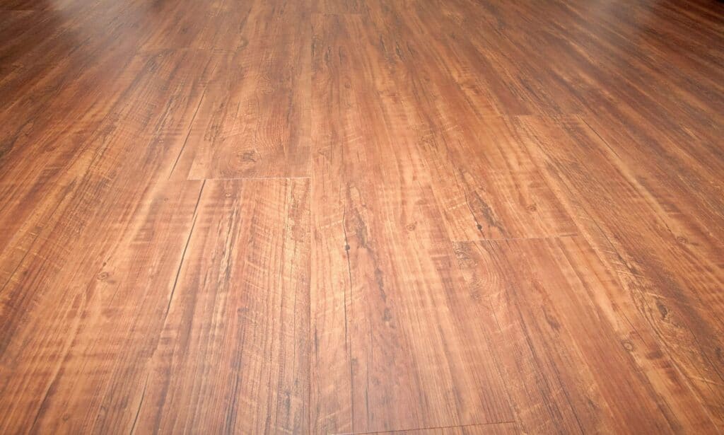close up view of a smooth, polished wooden floor with a warm brown tone and natural wood grain patterns running lengthwise across the surface.