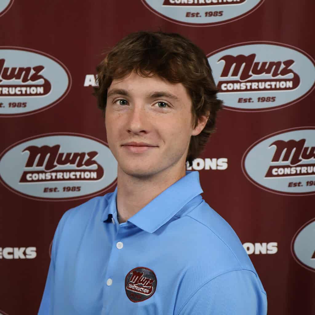 Team member at Munz Construction in front of company branding.
