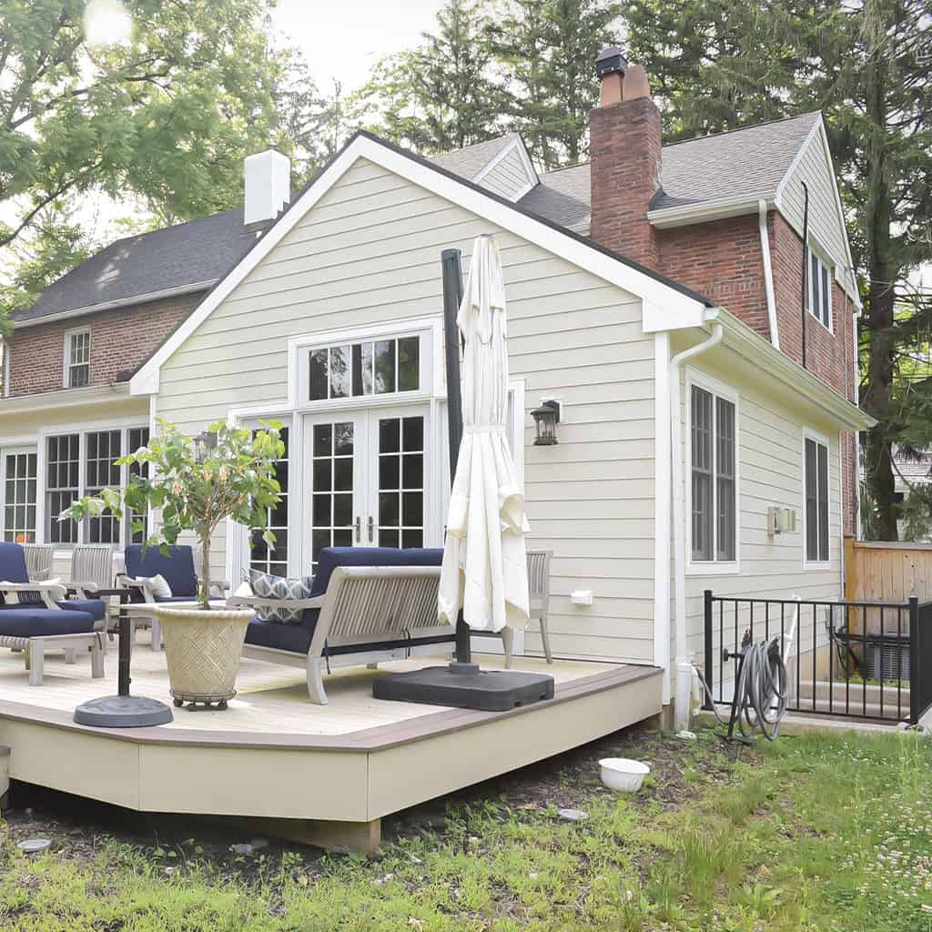 Beautiful house with a deck, outdoor furniture, and lush greenery.