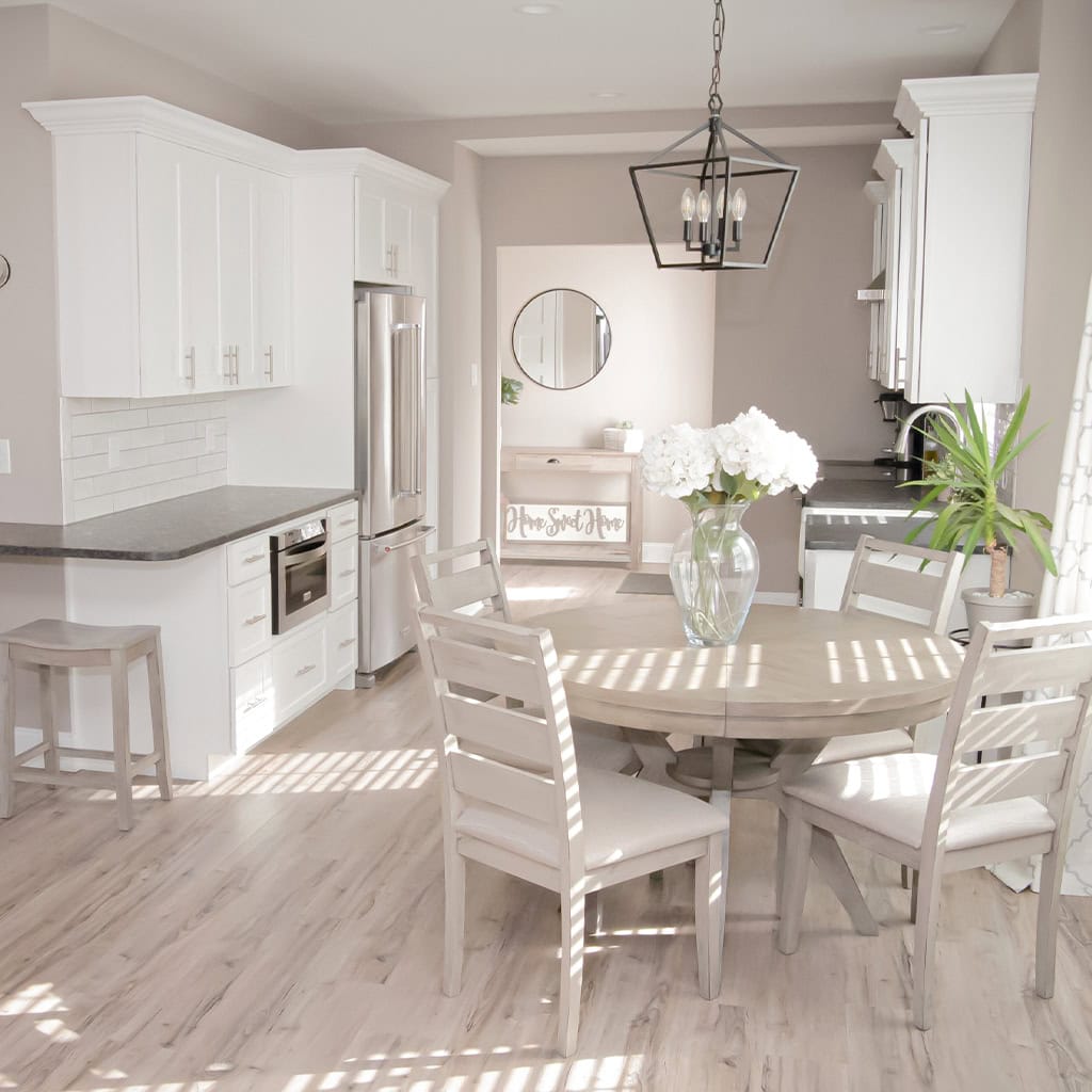 Bright modern kitchen with white cabinets and a round dining table with chairs.