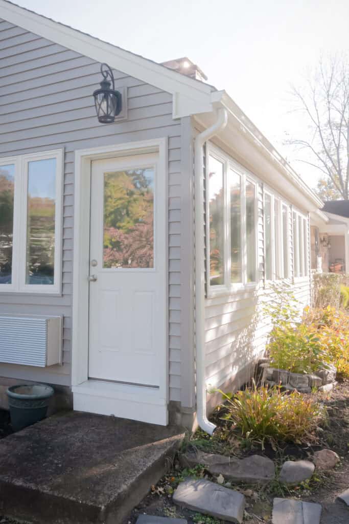 Bright sunroom with large windows and white siding, perfect for relaxing and enjoying sunlight.