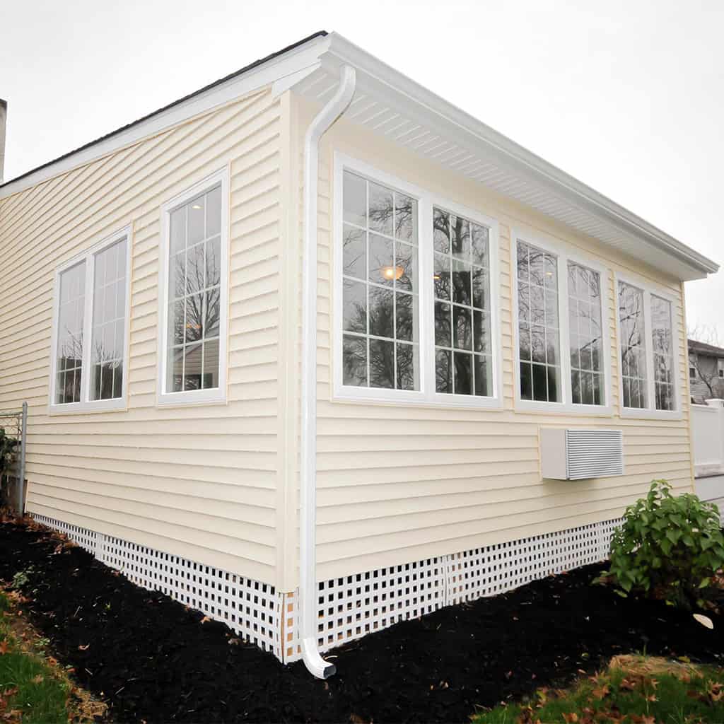Bright sunroom with large windows and white siding for natural light.
