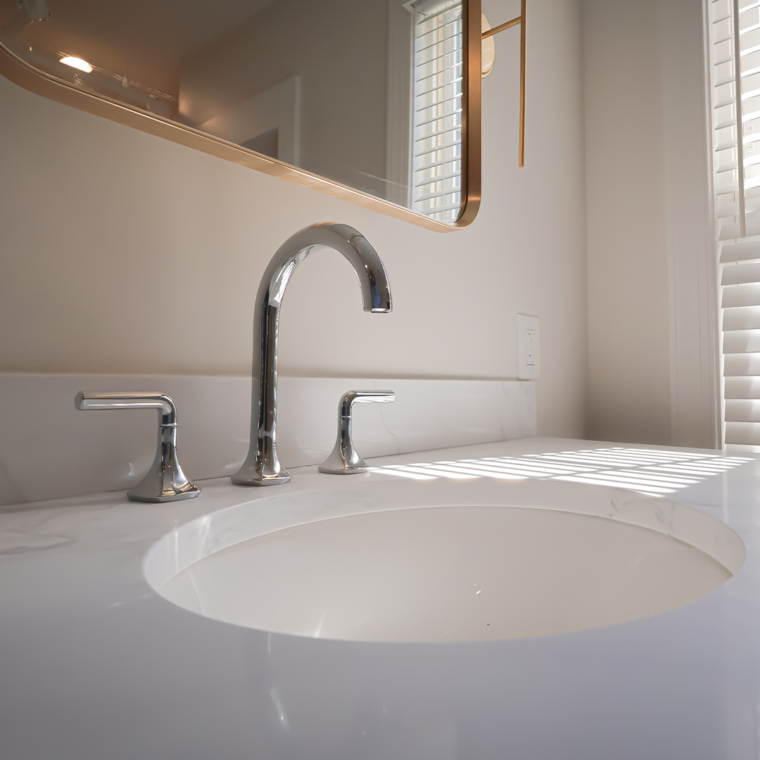 modern bathroom sink with a chrome faucet and handles, white countertop, and sunlight streaming through window blinds, reflecting softly on the surface. modern bathroom sink with a chrome faucet and handles, white countertop, and sunlight streaming through window blinds, reflecting softly on the surface.
