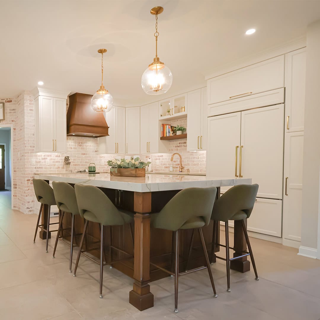 Kitchen island with four green bar stools facing white cabinets, a farmhouse sink, and two glass pendant lights. Kitchen island with four green bar stools facing white cabinets, a farmhouse sink, and two glass pendant lights.