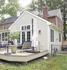 Beautiful house with a deck, outdoor furniture, and lush greenery.