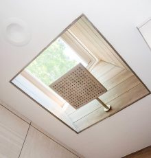 Modern skylight shower with wooden accents and natural light.