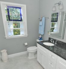 Modern bathroom with stained glass window and white fixtures.