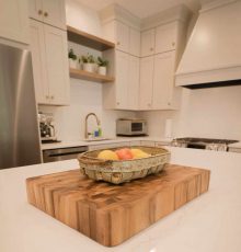 Bright modern kitchen with white cabinets and wooden island centerpiece.